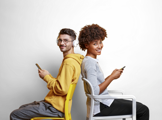 pareja usando celulares sentados de espalda